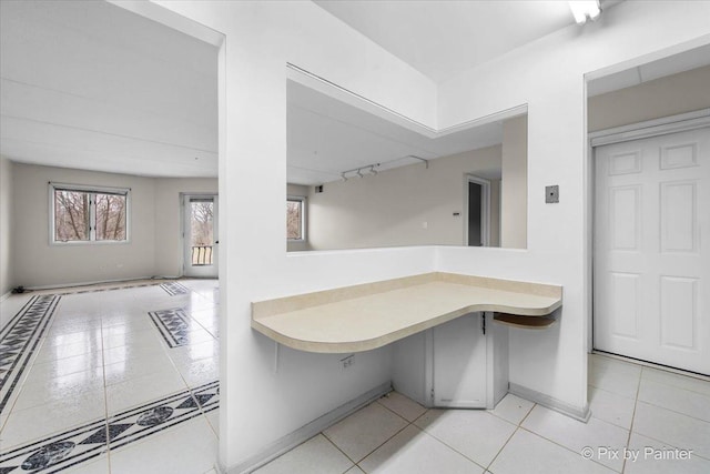 interior space featuring light countertops, open floor plan, tile patterned floors, and baseboards