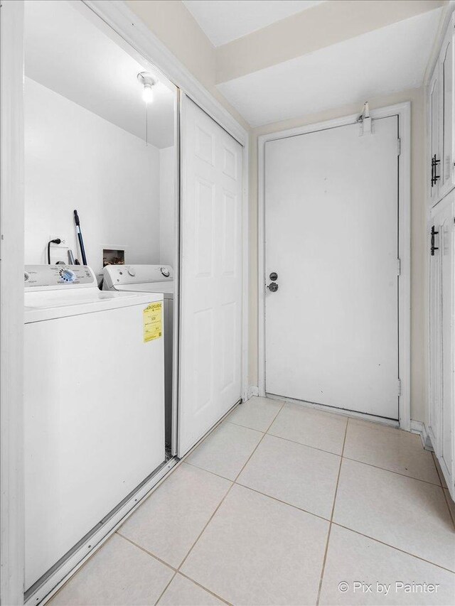 clothes washing area featuring washing machine and clothes dryer, laundry area, and light tile patterned floors