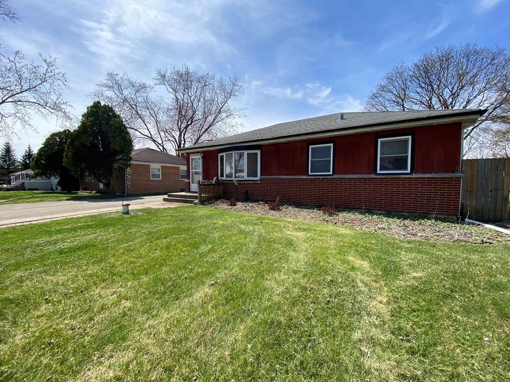 ranch-style home featuring brick siding, fence, and a front yard