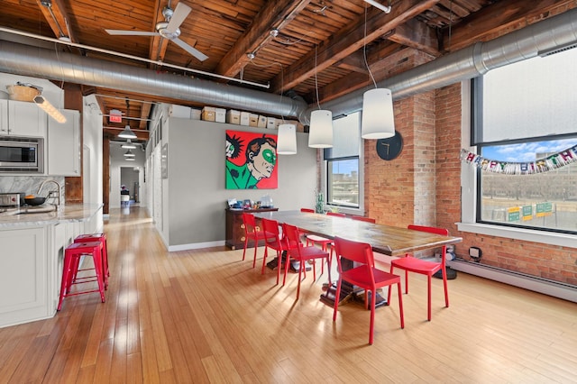 dining room featuring brick wall, wooden ceiling, ceiling fan, and light wood-style flooring