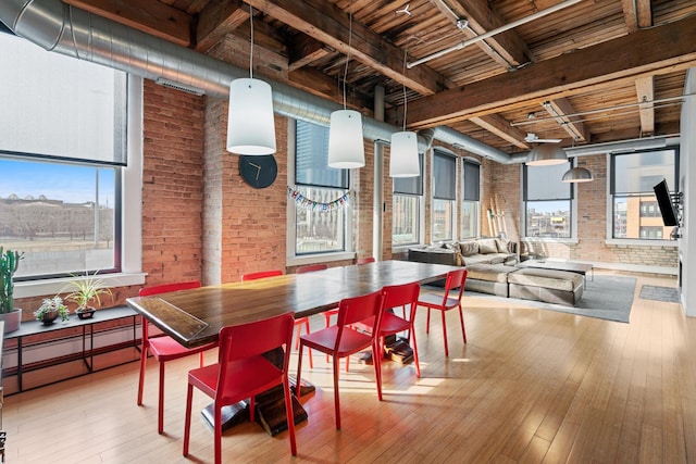 dining space featuring wood-type flooring, wooden ceiling, brick wall, and beamed ceiling