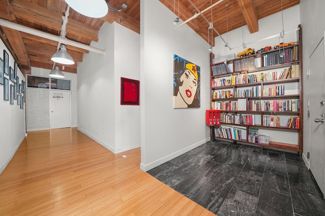 corridor with baseboards, beam ceiling, wood ceiling, and wood finished floors