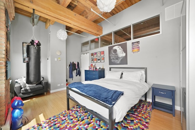 bedroom with wood finished floors, beam ceiling, baseboards, and wood ceiling