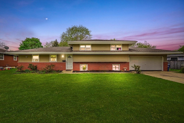split level home featuring a front yard, roof with shingles, brick siding, an attached garage, and driveway