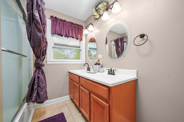 bathroom featuring tile patterned flooring, a sink, baseboards, and double vanity