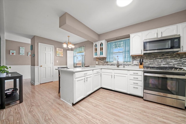 kitchen featuring light wood-style flooring, wainscoting, white cabinetry, and stainless steel appliances