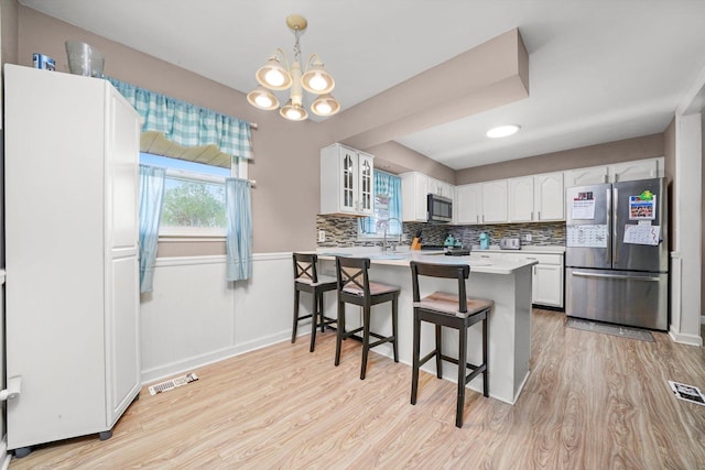 kitchen featuring a peninsula, light wood-style flooring, appliances with stainless steel finishes, and a kitchen bar