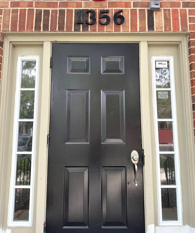 view of exterior entry featuring brick siding