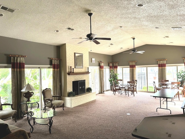 living area featuring carpet flooring, ceiling fan, a textured ceiling, lofted ceiling, and a fireplace