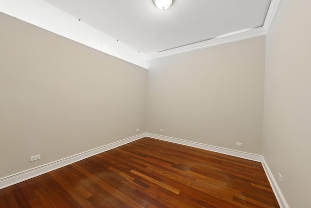 spare room featuring crown molding, baseboards, and dark wood-style flooring
