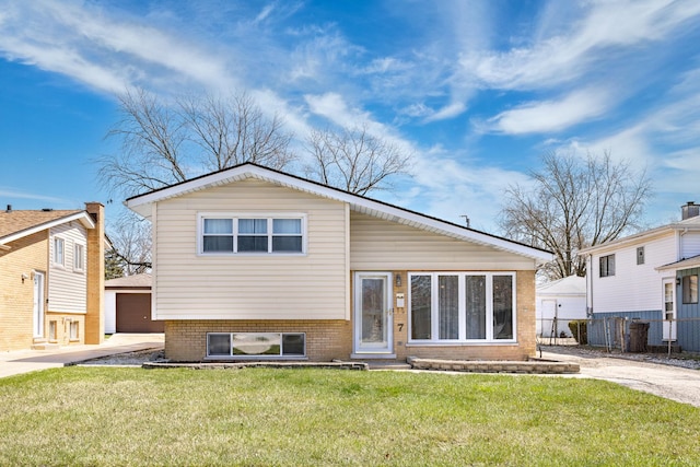 back of property with a yard, a detached garage, fence, an outdoor structure, and brick siding