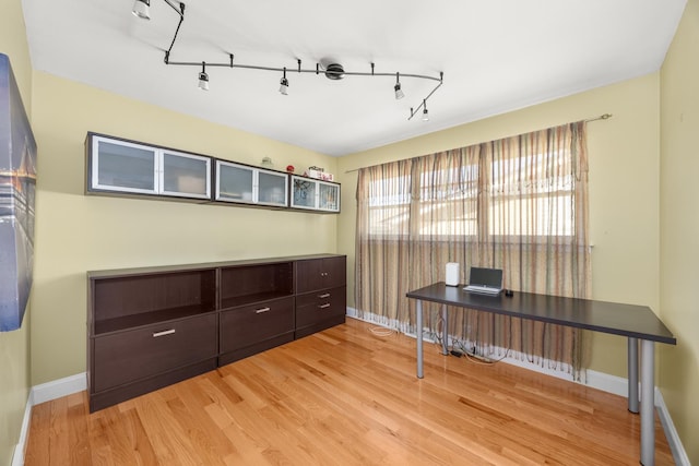 office area featuring light wood finished floors, track lighting, and baseboards