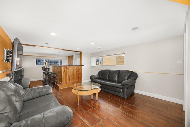 living room featuring bar, baseboards, recessed lighting, and wood finished floors