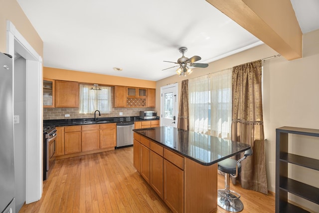 kitchen with tasteful backsplash, glass insert cabinets, a sink, stainless steel appliances, and a breakfast bar area