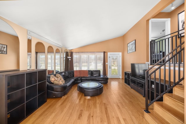 living room featuring vaulted ceiling, wood finished floors, and stairs