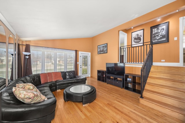 living room with vaulted ceiling, wood finished floors, and stairs