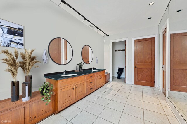 bathroom with baseboards, tile patterned flooring, a sink, and double vanity