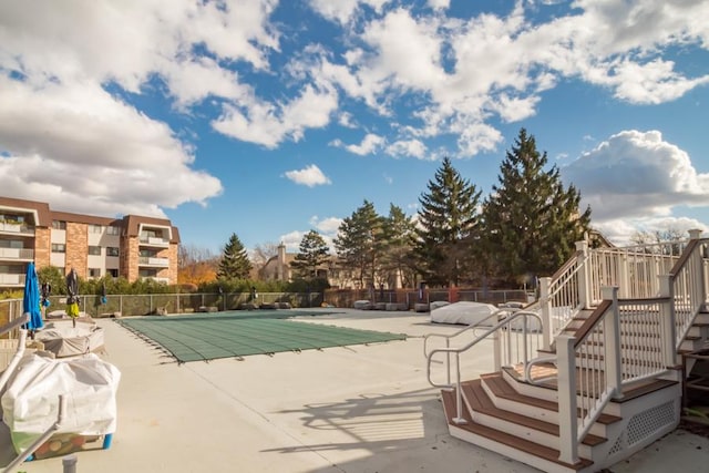 community pool featuring fence, stairs, and a patio