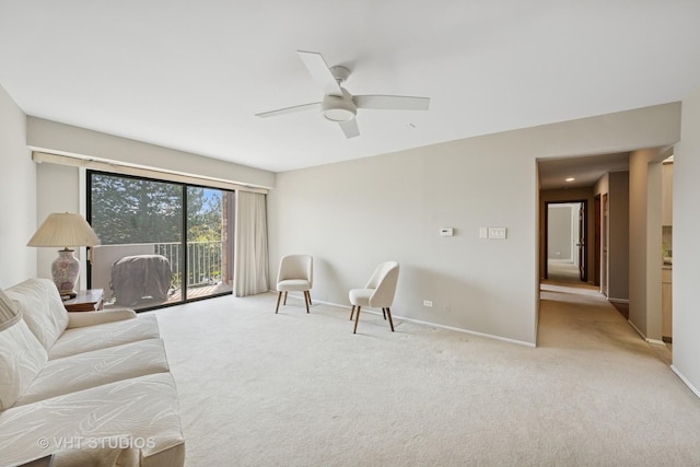 carpeted living area featuring baseboards and a ceiling fan