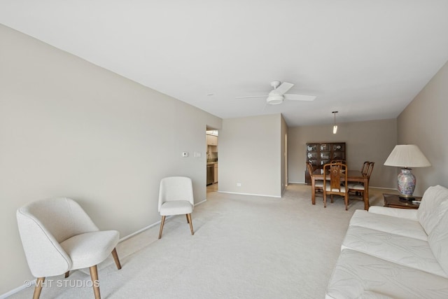 interior space with baseboards, ceiling fan, and light carpet