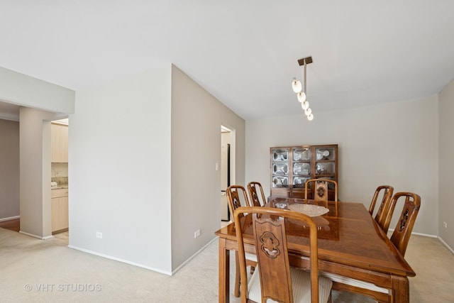 dining space with baseboards and light carpet