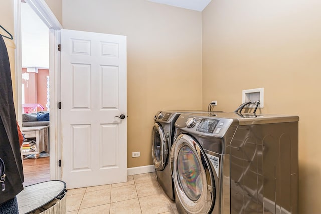 laundry area featuring baseboards, laundry area, washing machine and dryer, and light tile patterned floors