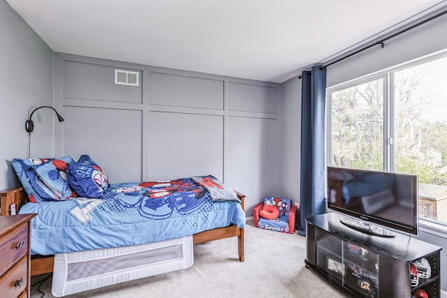 carpeted bedroom with visible vents and a decorative wall