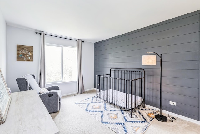 bedroom with carpet floors, baseboards, and a crib