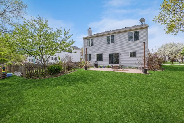 rear view of house with a yard, a patio, fence, and a chimney
