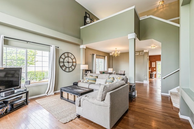 living area with a high ceiling, an inviting chandelier, stairs, baseboards, and hardwood / wood-style flooring