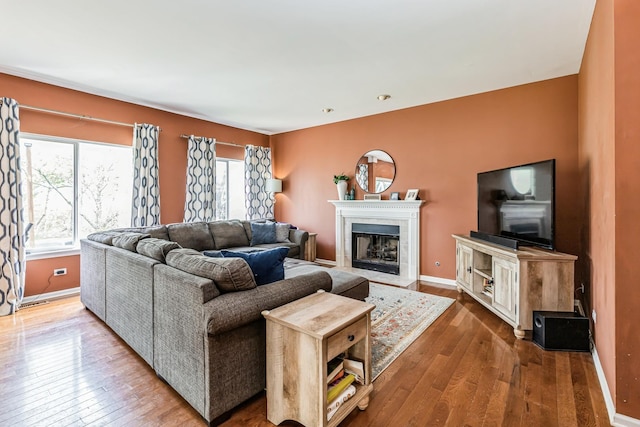 living area featuring plenty of natural light, a fireplace with flush hearth, baseboards, and hardwood / wood-style floors
