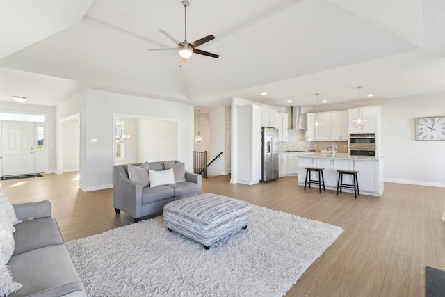 living area featuring recessed lighting, light wood-style floors, a ceiling fan, and baseboards