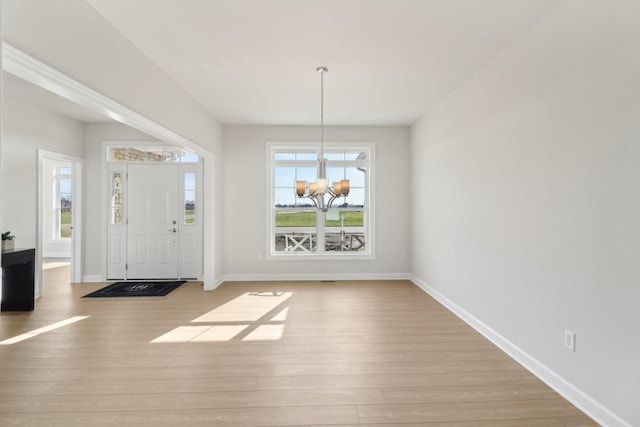 foyer entrance featuring wood finished floors, baseboards, and an inviting chandelier