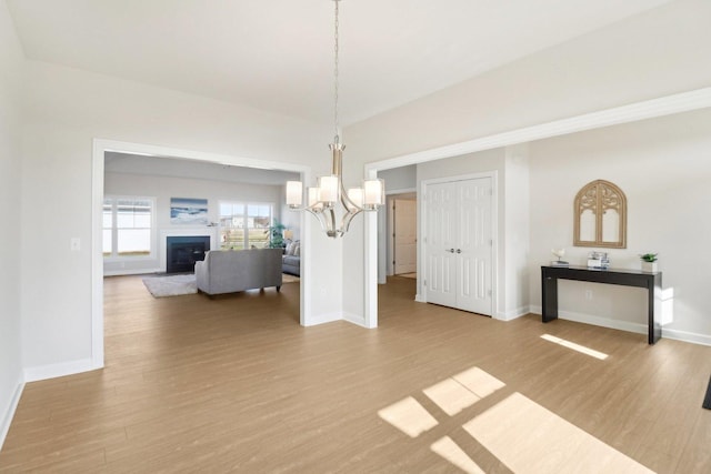 dining space with baseboards, a fireplace, wood finished floors, and an inviting chandelier