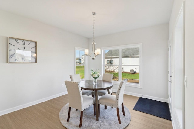 dining room with a chandelier, light wood-style floors, and baseboards