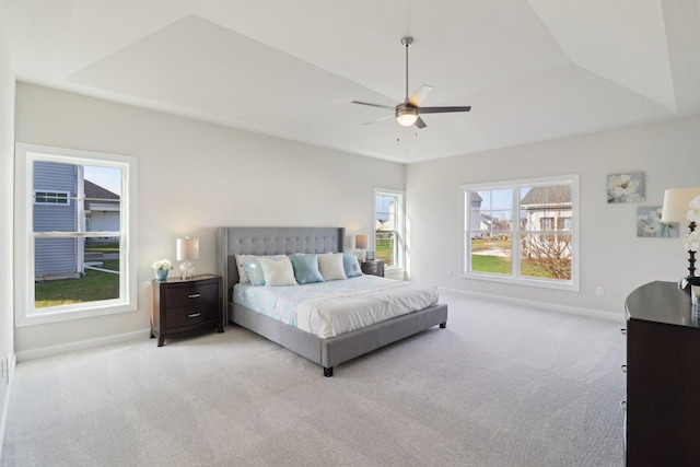 bedroom featuring baseboards, light carpet, and a raised ceiling