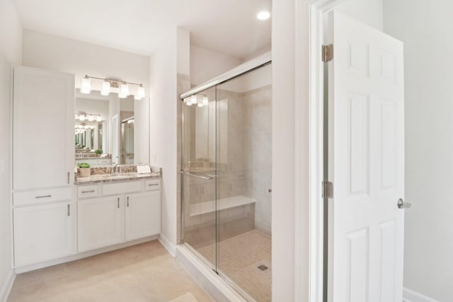 full bath with baseboards, vanity, and a stall shower