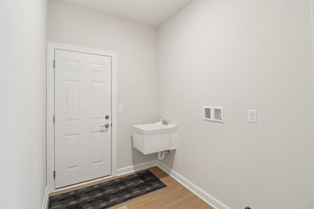 washroom featuring light wood finished floors, a sink, baseboards, washer hookup, and laundry area