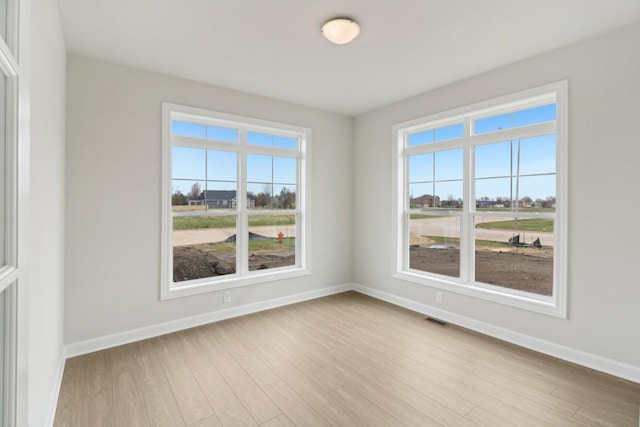spare room featuring visible vents, baseboards, and wood finished floors