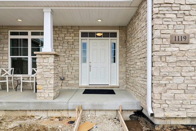 doorway to property featuring a porch and stone siding