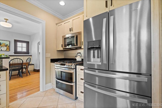 349 N Lincoln St, Batavia, IL 60510 - kitchen with dark countertops, ornamental molding, light tile patterned floors, arched walkways, and appliances with stainless steel finishes