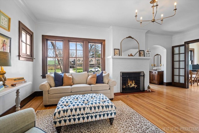 349 N Lincoln St, Batavia, IL 60510 - living area featuring arched walkways, light wood-type flooring, a notable chandelier, a brick fireplace, and ornamental molding