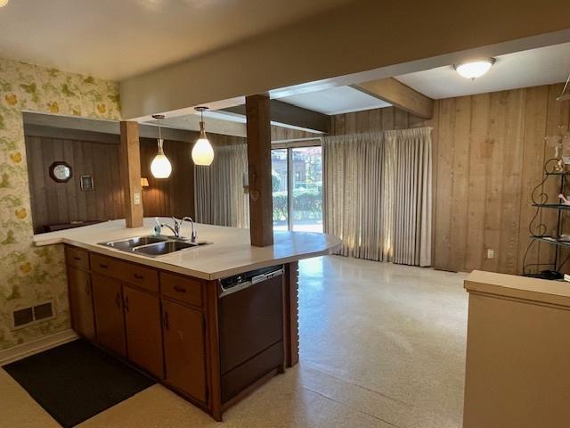 kitchen with a sink, dishwasher, a peninsula, wallpapered walls, and visible vents