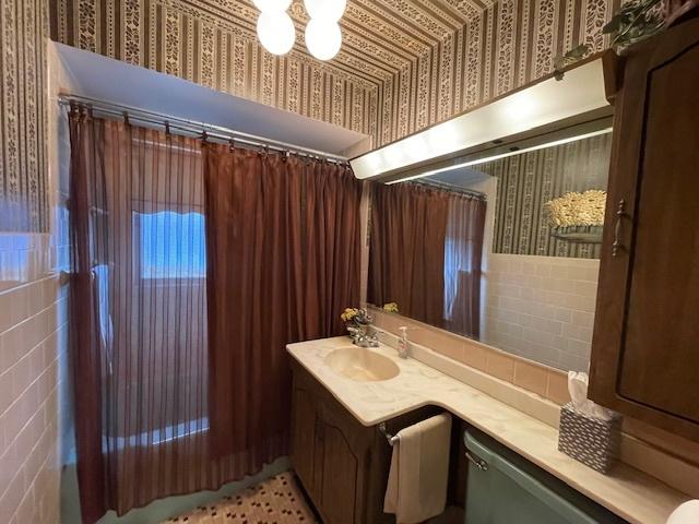 bathroom featuring vanity, tile walls, and wallpapered walls