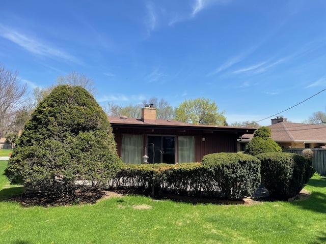 view of side of home featuring a lawn and a chimney
