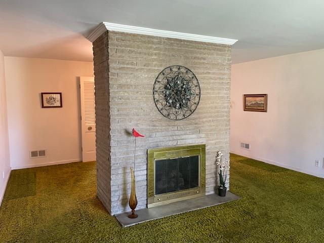unfurnished living room featuring carpet floors, visible vents, and a brick fireplace