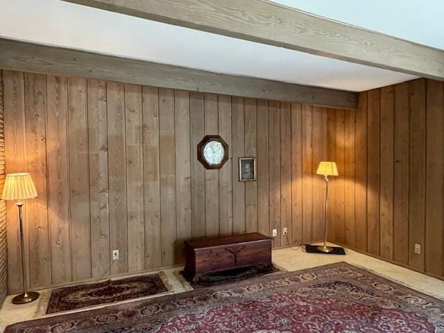 living area featuring carpet floors, beam ceiling, and wooden walls
