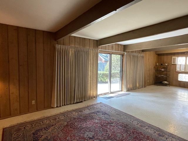 interior space with wooden walls, carpet, and beam ceiling
