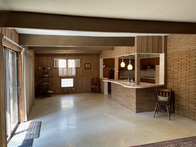interior space with wooden walls, a sink, ventilation hood, beam ceiling, and freestanding refrigerator