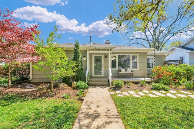 view of front of house featuring a porch, a chimney, and a front yard